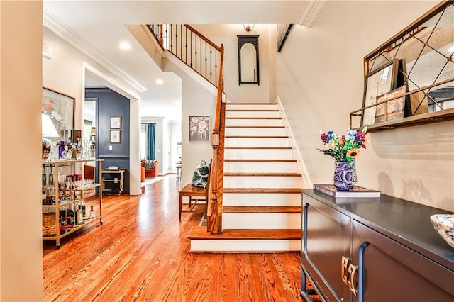 stairway featuring recessed lighting, ornamental molding, and wood finished floors