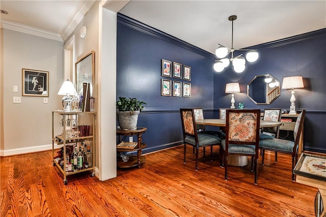 dining space with crown molding, baseboards, an inviting chandelier, and wood finished floors