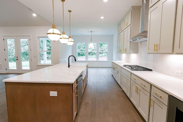 kitchen with wall chimney exhaust hood, appliances with stainless steel finishes, pendant lighting, and a large island