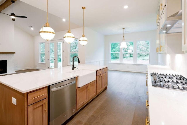 kitchen with pendant lighting, light countertops, appliances with stainless steel finishes, open floor plan, and a sink