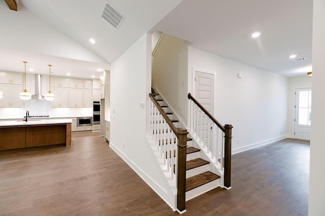 staircase with baseboards, visible vents, wood finished floors, vaulted ceiling, and recessed lighting