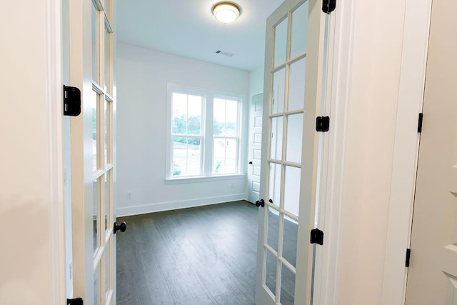 unfurnished room with baseboards, visible vents, dark wood-type flooring, and french doors