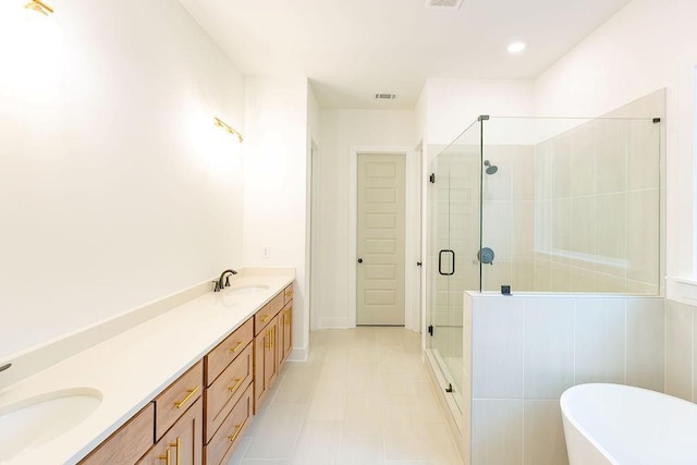 bathroom with a freestanding bath, double vanity, a stall shower, and a sink