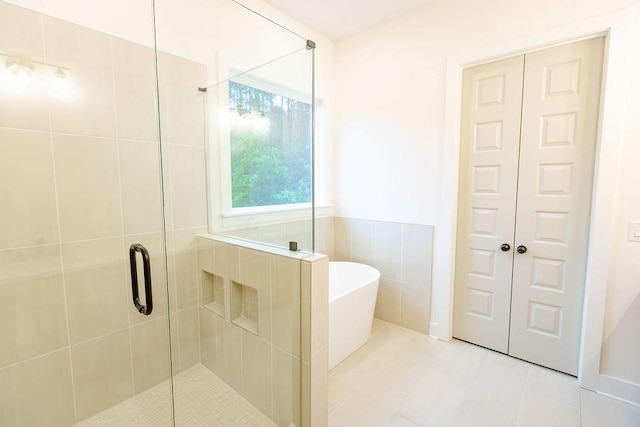 full bathroom featuring a stall shower, a freestanding tub, tile walls, and tile patterned floors