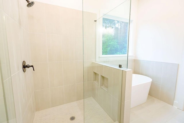 bathroom with a freestanding tub, a walk in shower, and tile walls