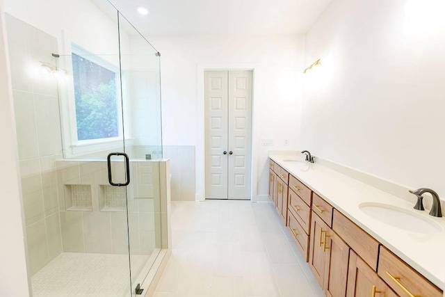 full bath featuring a stall shower, tile patterned flooring, a sink, and double vanity