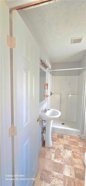 bathroom featuring walk in shower and a textured ceiling