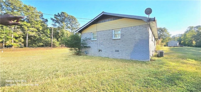 view of side of home with central AC and a lawn