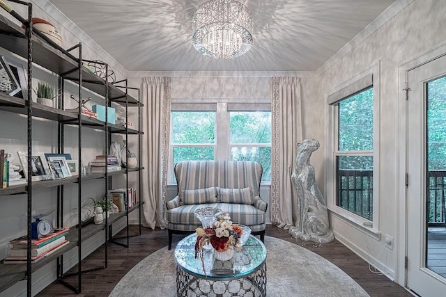 sitting room with a wealth of natural light, a notable chandelier, wood finished floors, and crown molding