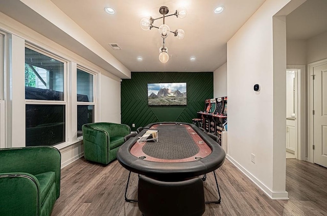 rec room with visible vents, baseboards, wood finished floors, and an accent wall