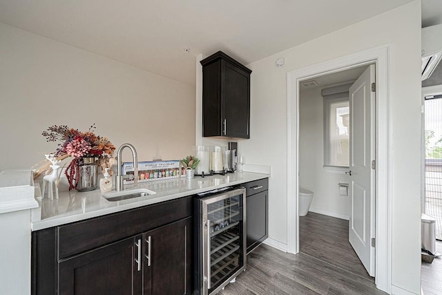 kitchen featuring beverage cooler, a sink, dark wood-style floors, light countertops, and baseboards