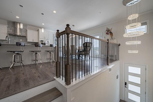 stairs featuring a notable chandelier, recessed lighting, wood finished floors, and ornamental molding