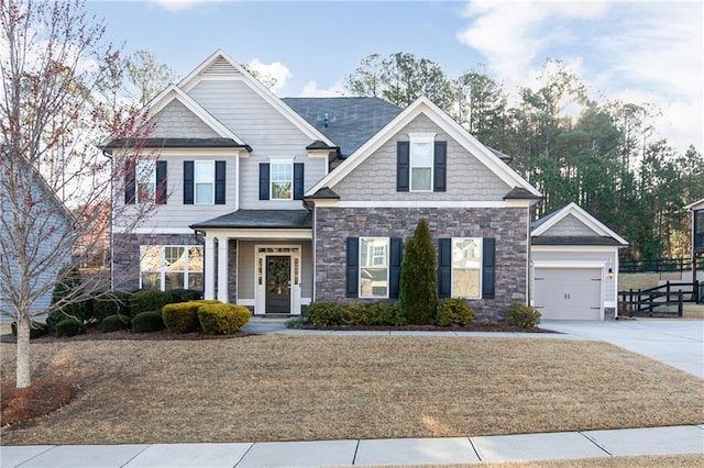 craftsman-style home with stone siding, a garage, and driveway