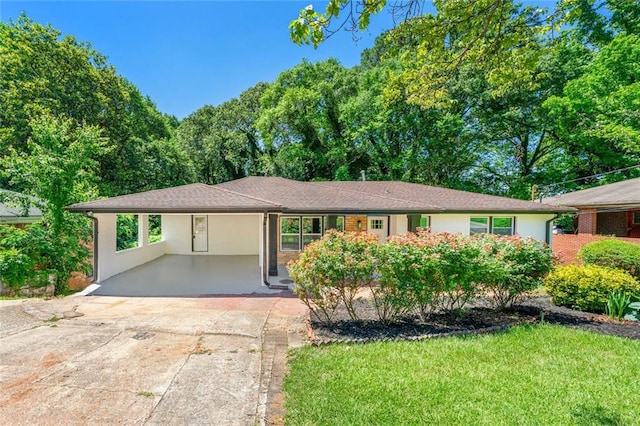 single story home with driveway, an attached carport, a front lawn, and stucco siding