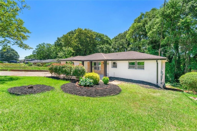 ranch-style home featuring a front lawn and stucco siding