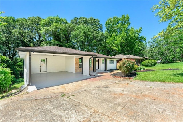 view of front facade with a carport, concrete driveway, and a front lawn