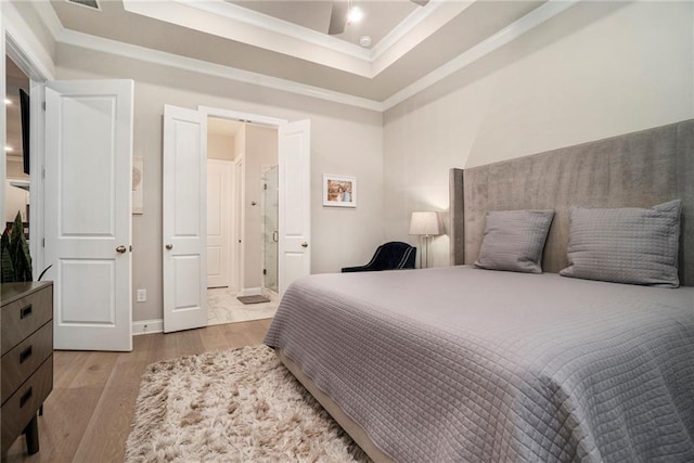 bedroom featuring crown molding, a raised ceiling, wood finished floors, and visible vents