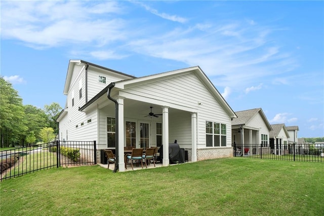 rear view of property featuring a lawn, a patio, ceiling fan, and a fenced backyard