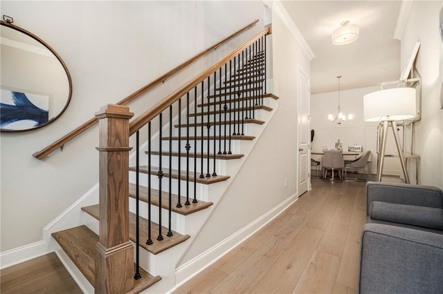 stairway with wood-type flooring, baseboards, and an inviting chandelier