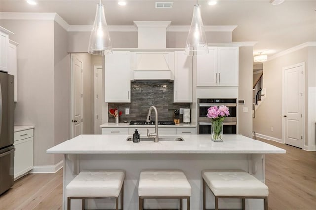 kitchen featuring visible vents, appliances with stainless steel finishes, tasteful backsplash, a sink, and ornamental molding