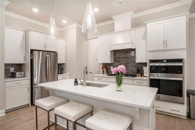 kitchen featuring a sink, a breakfast bar area, stainless steel appliances, decorative backsplash, and ornamental molding
