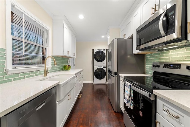 2903 Akron St, East Point, GA 30344 - kitchen featuring appliances with stainless steel finishes, estacked washer and dryer, backsplash, dark wood-type flooring, and ornamental molding