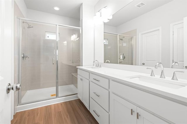 bathroom with hardwood / wood-style floors, vanity, and a shower with shower door