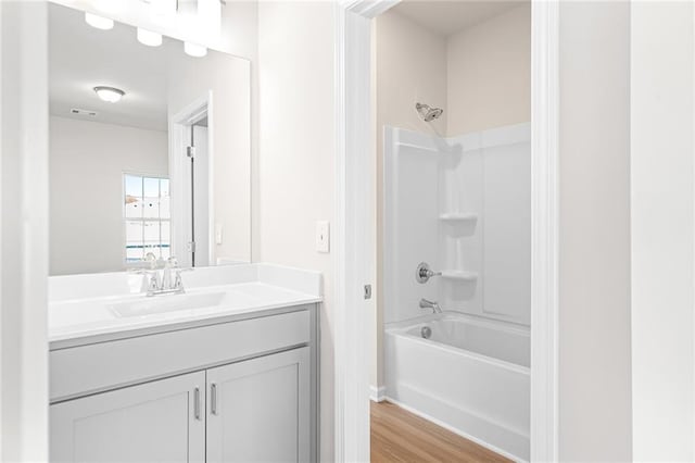 bathroom with hardwood / wood-style flooring, vanity, and  shower combination