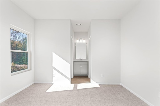 spare room featuring light colored carpet and sink