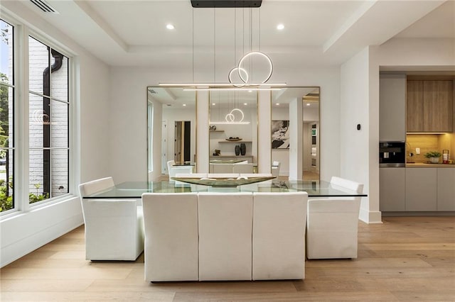 dining room with light hardwood / wood-style floors and a tray ceiling