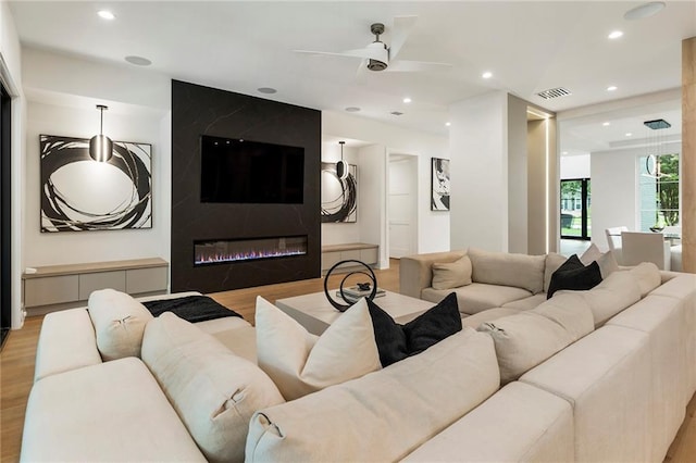 cinema room featuring a fireplace, light wood-type flooring, and ceiling fan