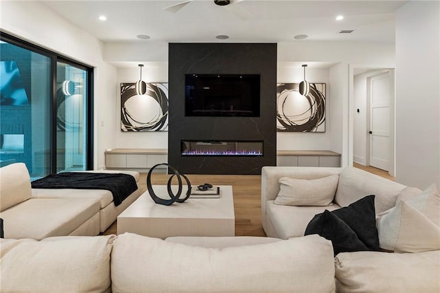 living room featuring ceiling fan, light hardwood / wood-style flooring, and a fireplace