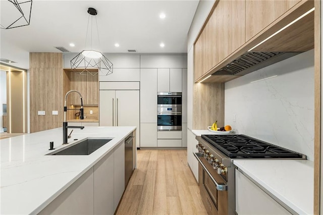 kitchen featuring light stone countertops, pendant lighting, sink, custom range hood, and high quality appliances