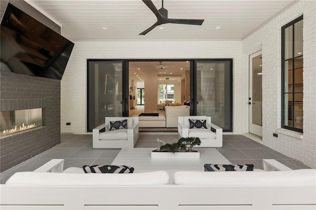 view of patio / terrace featuring ceiling fan and an outdoor living space with a fireplace