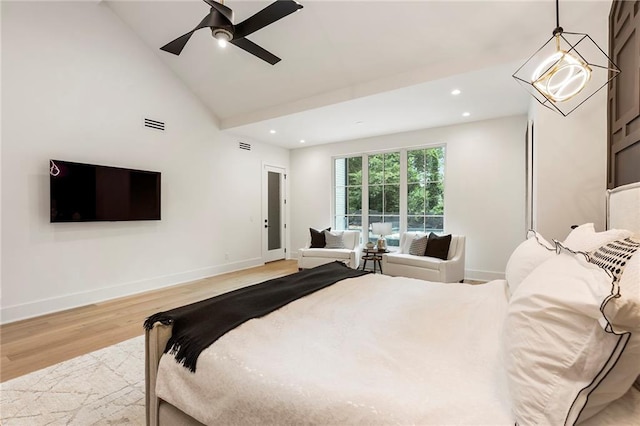 bedroom featuring ceiling fan with notable chandelier, light hardwood / wood-style floors, and high vaulted ceiling