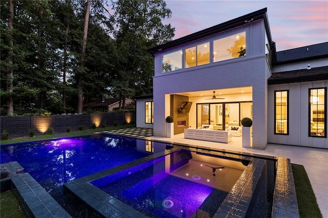 pool at dusk with an in ground hot tub, a patio, and ceiling fan