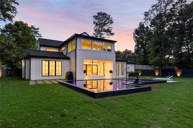 back house at dusk with a lawn and a patio