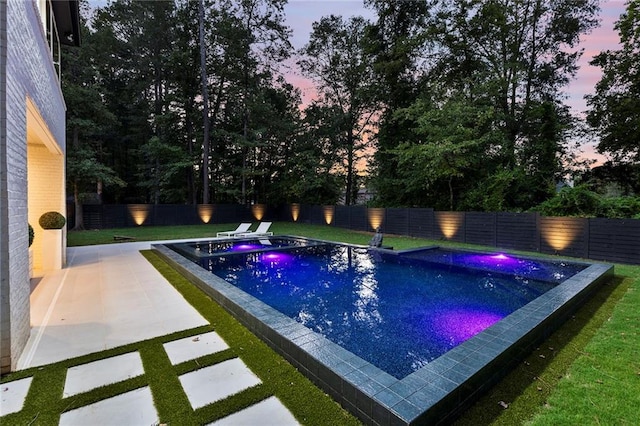 pool at dusk featuring a patio