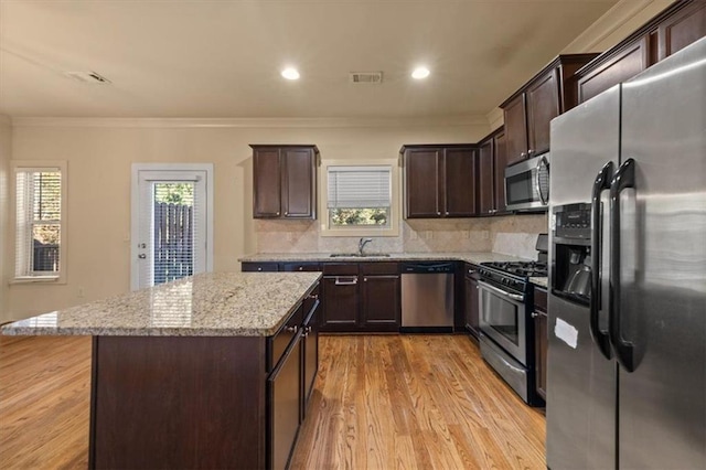 kitchen featuring a center island, a healthy amount of sunlight, light wood-type flooring, and appliances with stainless steel finishes