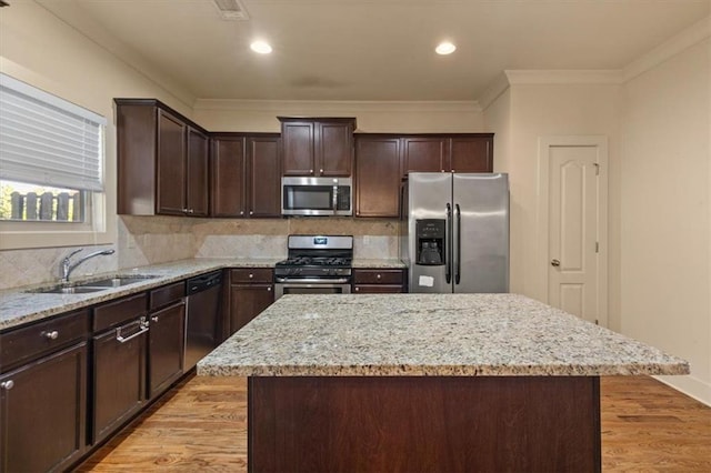 kitchen with backsplash, sink, a kitchen island, and appliances with stainless steel finishes