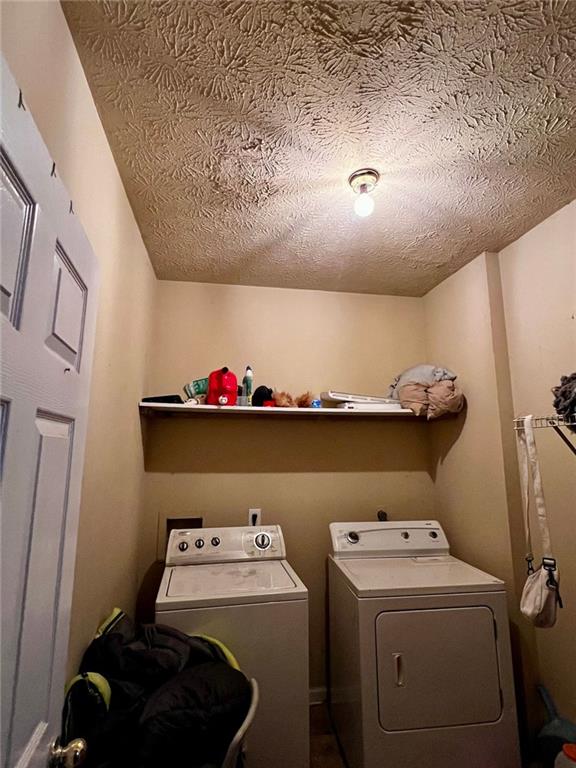 washroom featuring washing machine and dryer and a textured ceiling