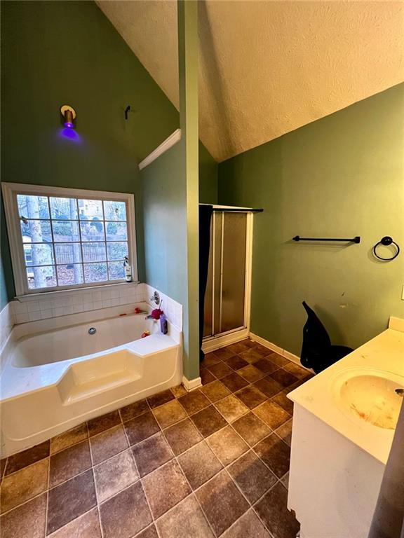 bathroom with lofted ceiling, vanity, and shower with separate bathtub