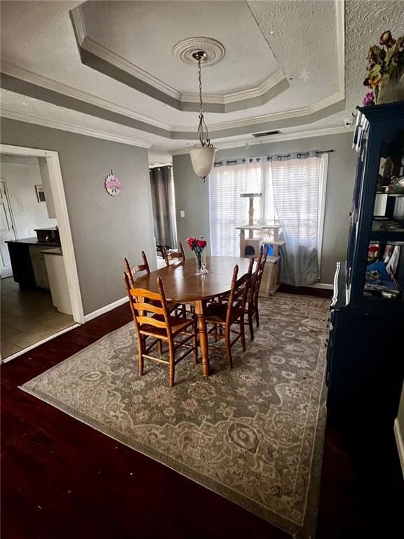 dining area featuring crown molding, a raised ceiling, and a textured ceiling