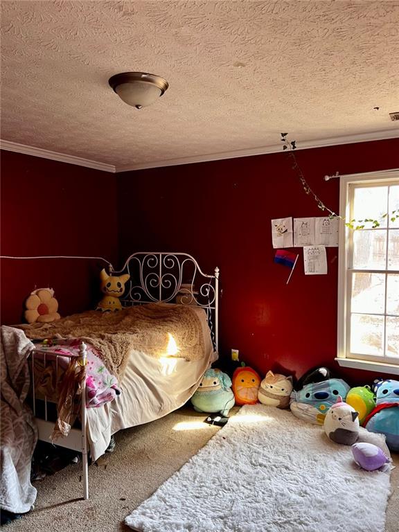 carpeted bedroom with ornamental molding and a textured ceiling