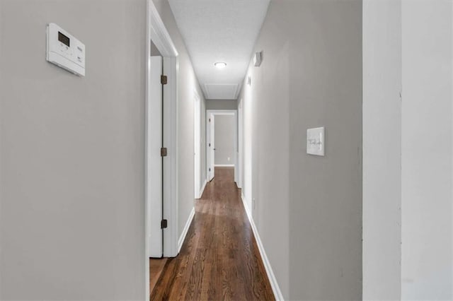 hallway featuring dark wood finished floors and baseboards