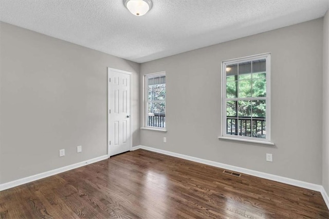 spare room with baseboards, a wealth of natural light, and wood finished floors