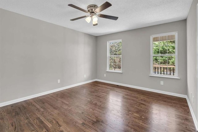 empty room featuring dark wood-style floors, a wealth of natural light, and baseboards