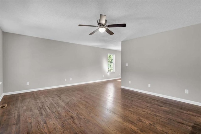 spare room featuring dark wood finished floors, visible vents, a ceiling fan, a textured ceiling, and baseboards