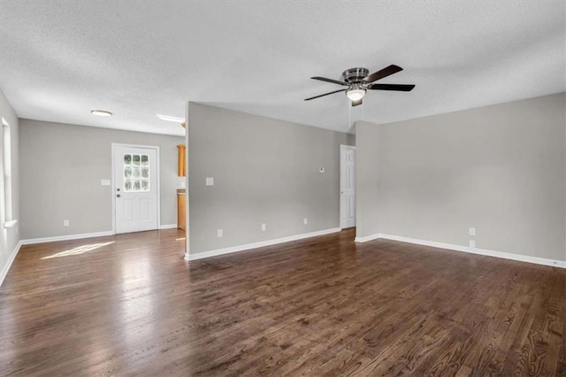 unfurnished living room featuring ceiling fan, a textured ceiling, dark wood finished floors, and baseboards