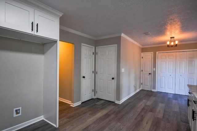 interior space with a notable chandelier, crown molding, dark wood-type flooring, and a textured ceiling